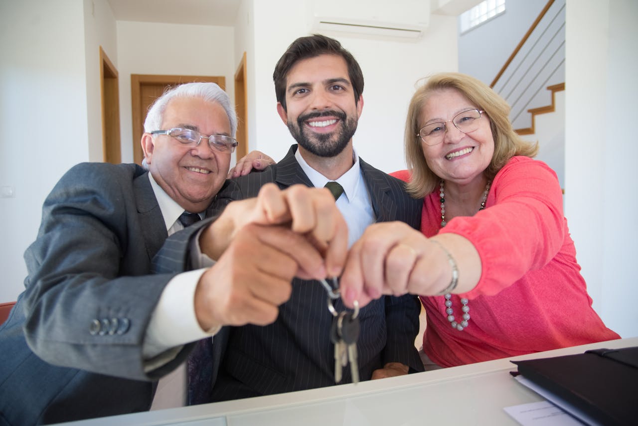 A couple holding keys next to a man in a suit jacket. Image by Pexels