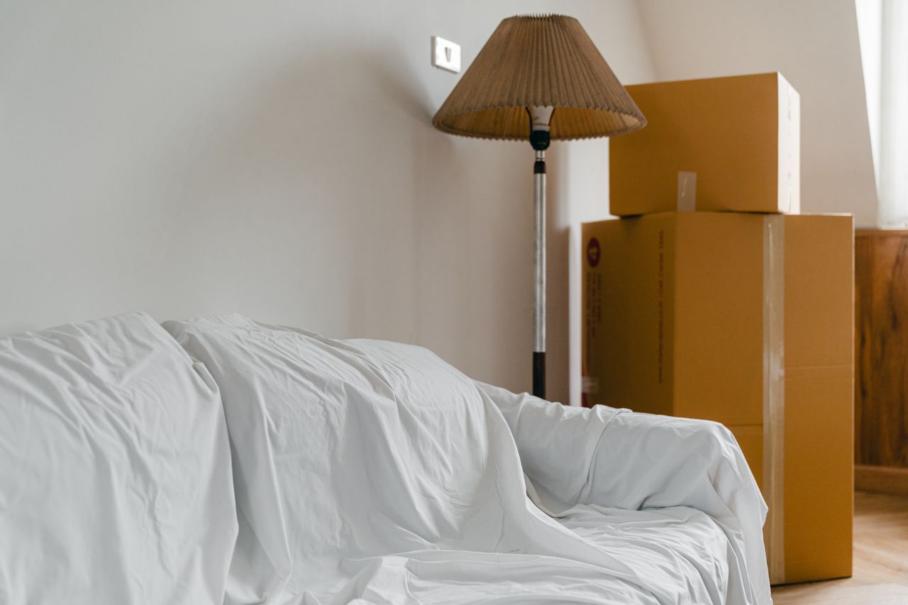 Packed boxes and a piece of furniture in a new house room. Image by Pexels