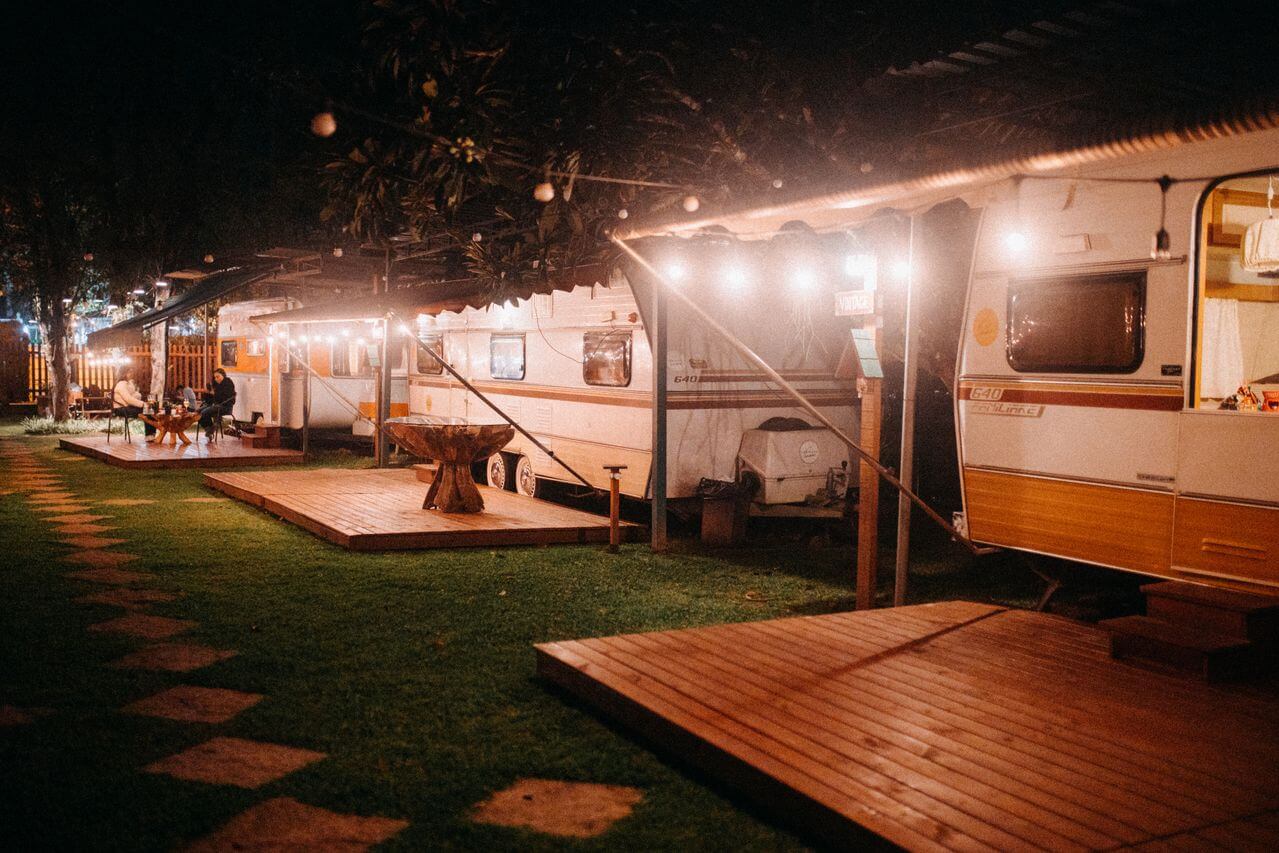 A serene night scene at a campsite with caravans, well-lit pathways, and people enjoying the outdoor ambiance. Image by Pexels