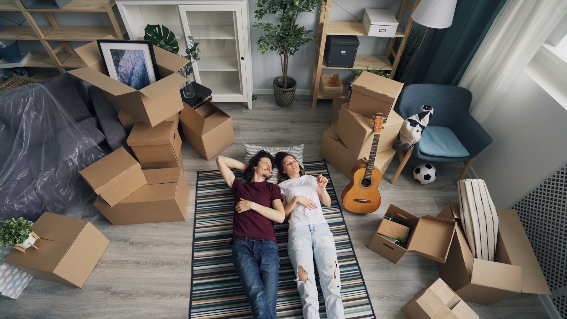 People laying on the floor surrounded by moving boxes. Image by Unsplash