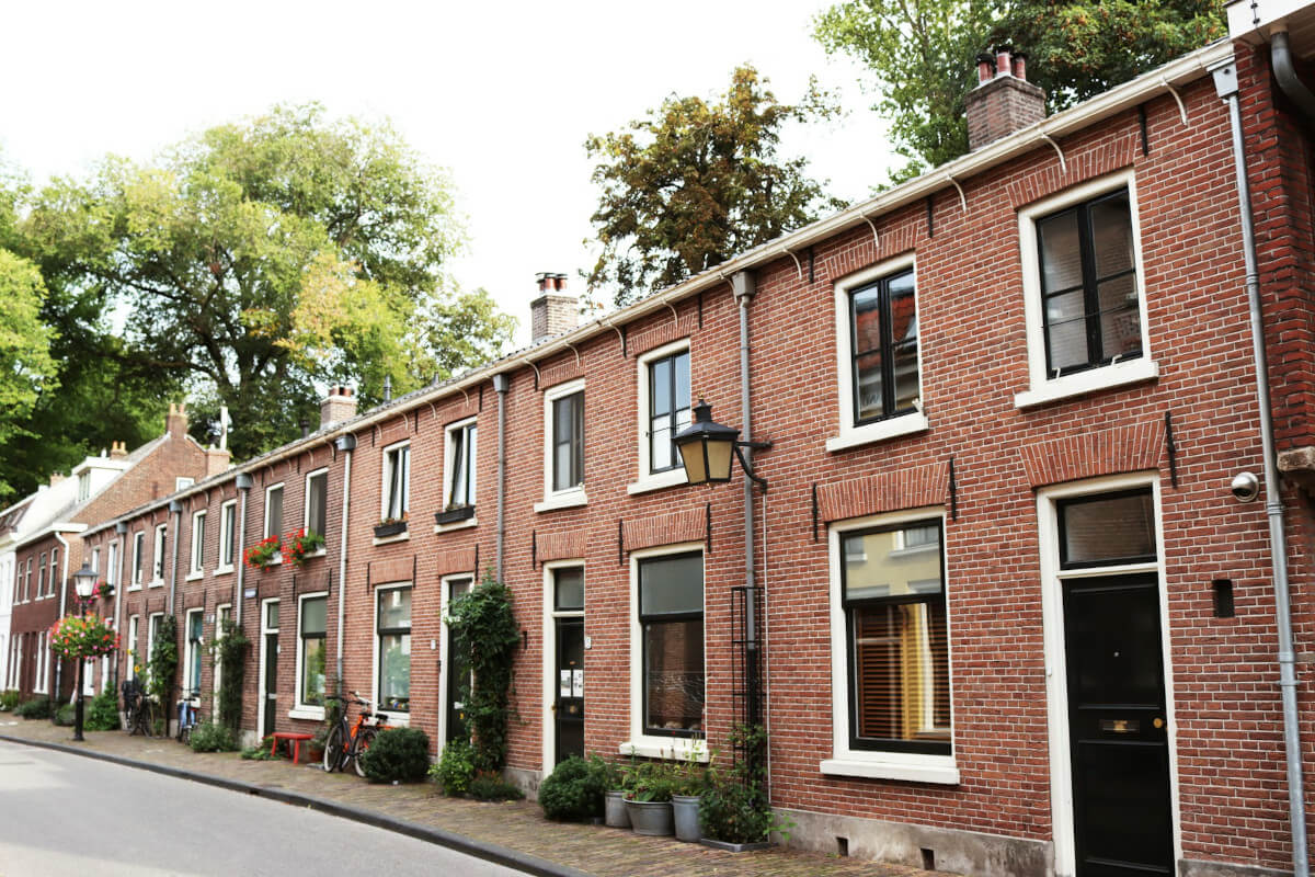 Brick housing, trees in the background. Image by Unsplash