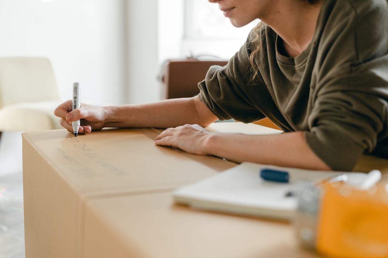 Person writing on a box. Image by Pexels