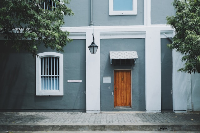 Wooden door on a gray and white building. Image by Unsplash