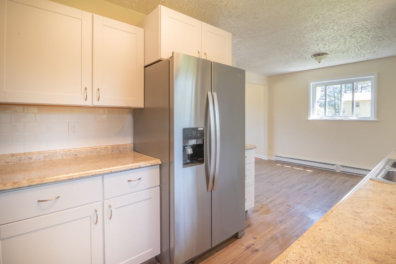 Stainless refrigerator in a white cabinet kitchen. Image by Pexels