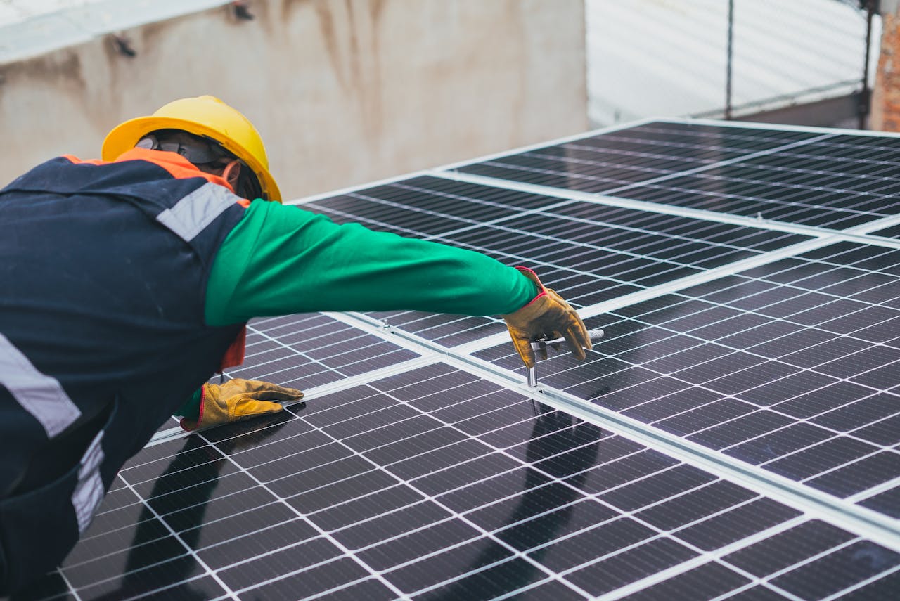 person installing solar panels on a roof. Image by Pexels