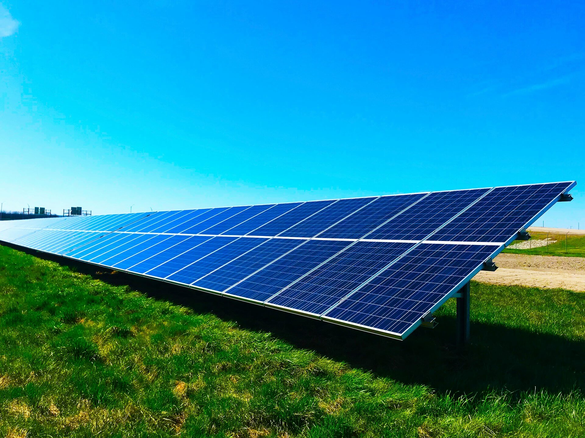Solar panels on grass, blue sky. Image by Unsplash