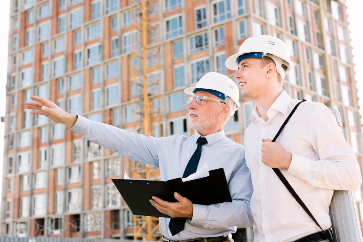 2 people with white hard hats, one person pointing at something.