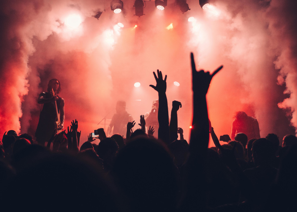 People at a concert, smoke, hands in the air