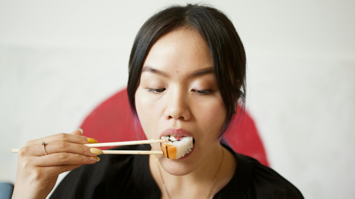 person eating sushi with chopsticks
