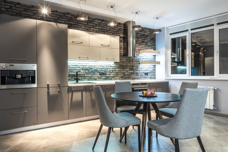 Modern kitchen, dining table and four chairs near the kitchen counter and cabinets