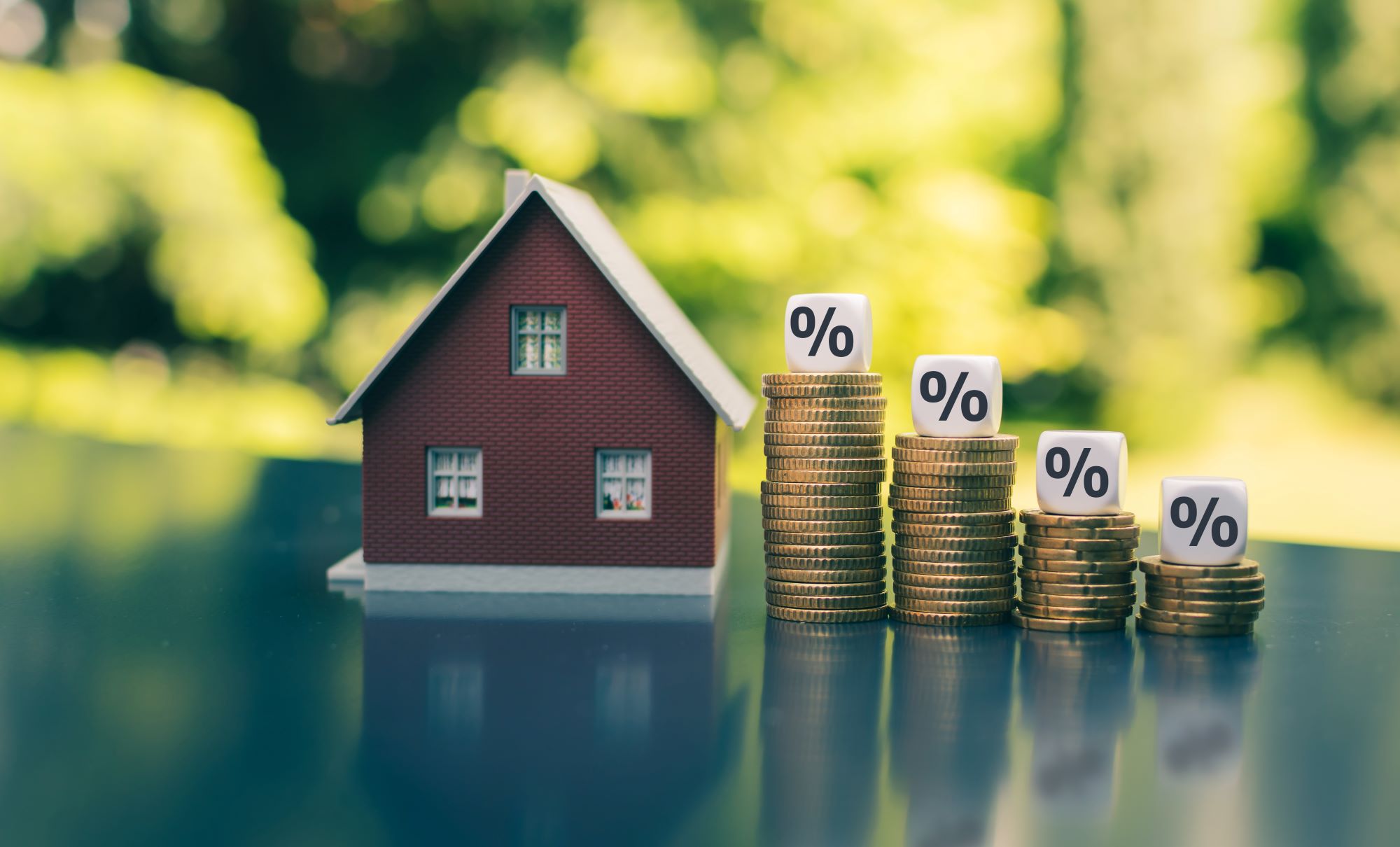 A red house on a table. Four stacks of coins with a white dice that says % on top of them next to the house.