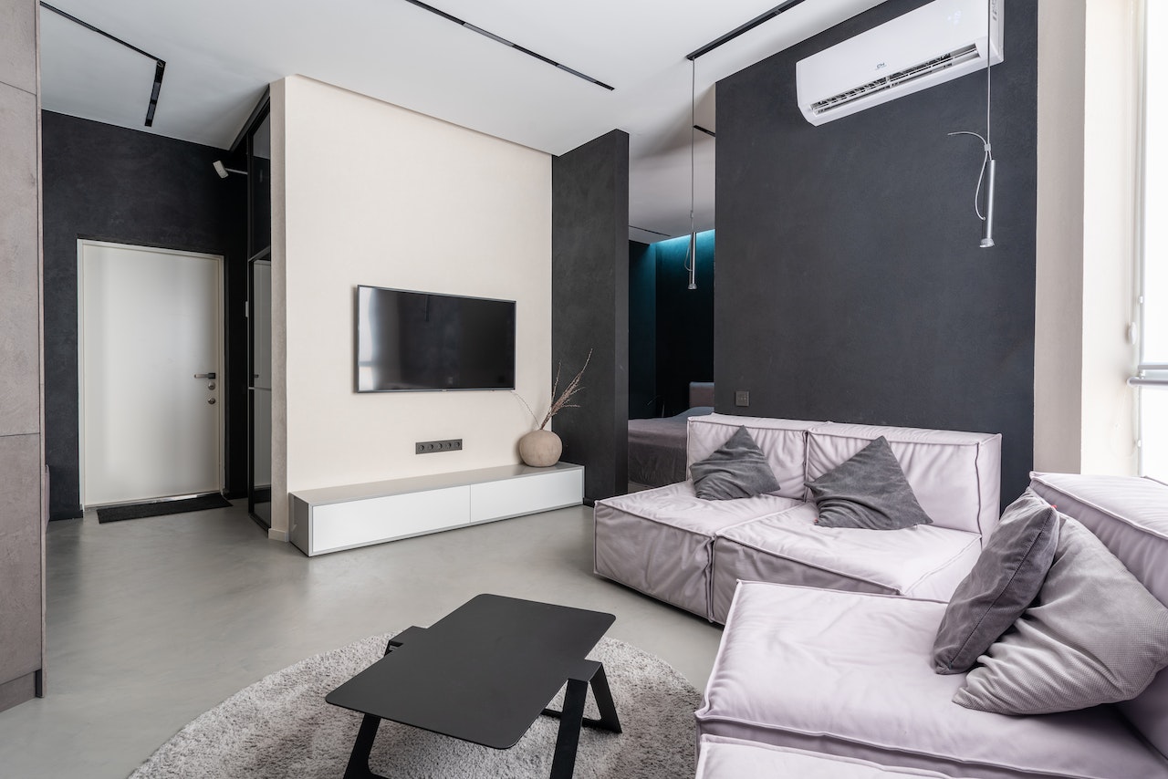 Livingroom, tv in wall, air conditioning unit on wall, grey and white walls, sofas and table