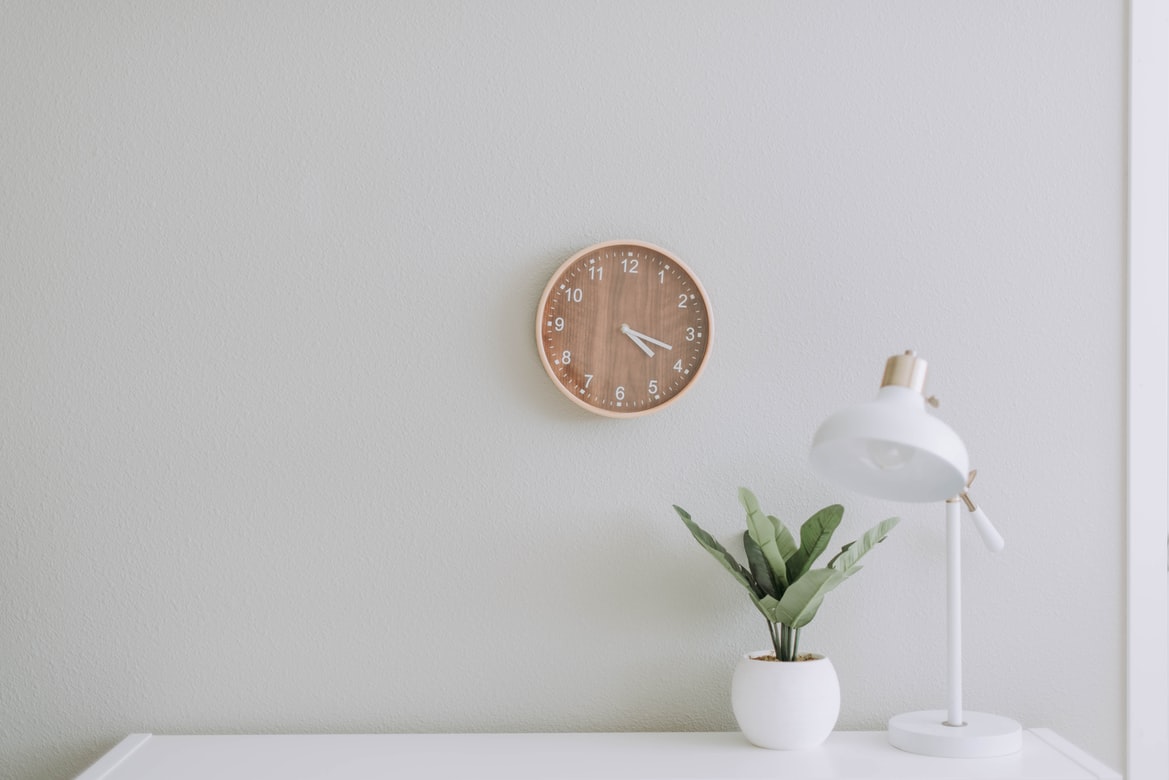 table with plant and lamp, clock on wall