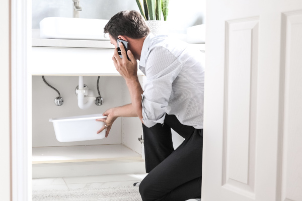 Man holding bucket under sink