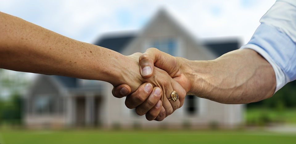 people shaking hands in front of a house