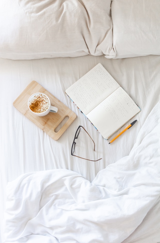 pen, glasses, book on a bed