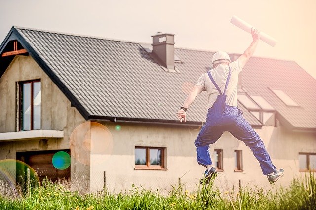 Person jumoiung with papers in his hands in front of a house