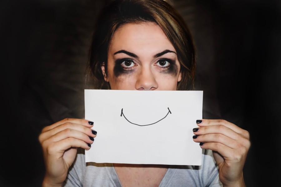 Peron holding up a piece of paper with a happy mouth in front of her face.