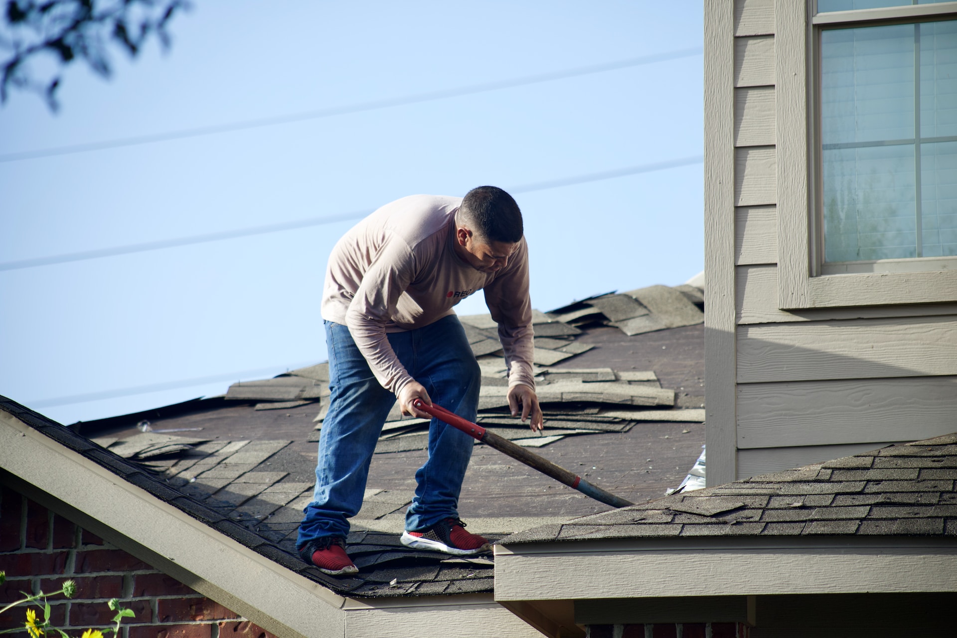 person removing roof shingles