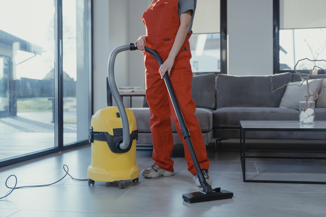 person in orange clothing vacuuming