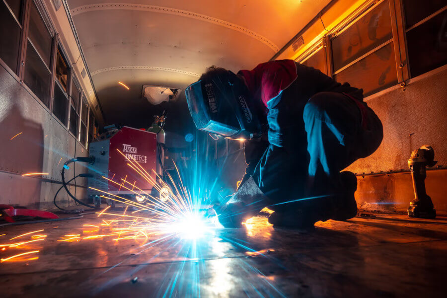 A mechanic welds steel that makes sparks fly