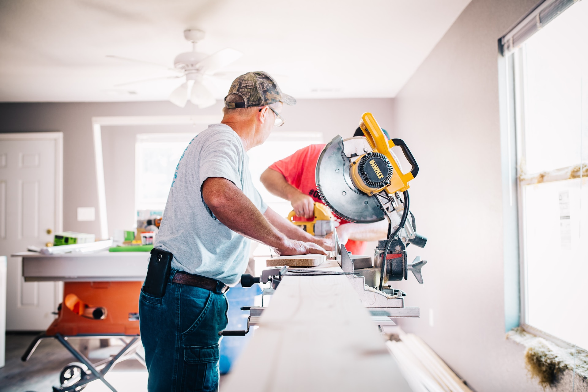 2 people doing renovations in a home, big yellow saw, yellow drill